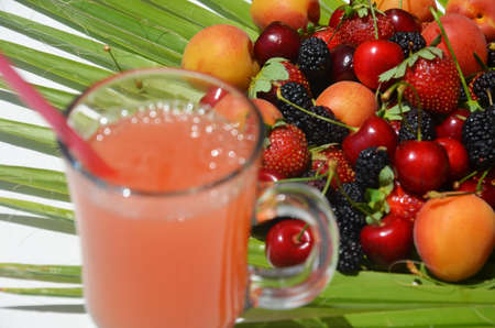 extremely close up glass of tasty tropical alcohol cocktail with berries or lemonade with beautiful decoration on a table in a restaurant with backgrounds of bright colored lights. soft focus.の写真素材