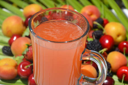 Traditional summer drink sangria. summer Tropical berry or fruit drink. fresh juice. cold refreshing tea. berry smoothies. alcoholic or non-alcoholic drink, cocktail. Against the background of berries and fruit, cherries, apricots, mulberry, strawberries against the background of a palm leafの写真素材