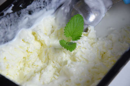 Close up vanila ice cream in container with leaf mint and spoon. Scoop of pistachio or mint ice creamの写真素材