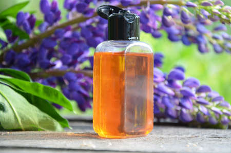 brown jar with oil. organic cosmetic with purple flowers and oil on foliage background. spa concept, perfumeryの写真素材