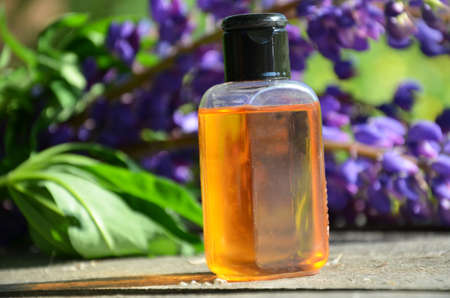 brown jar with oil. organic cosmetic with purple flowers and oil on foliage background. spa concept, perfumeryの写真素材