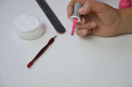 The girl does manicure nails nail file undermining with pink nail polish. Close-up of a hand nearの写真素材