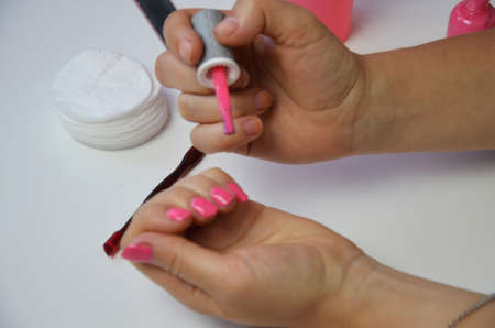 The girl does manicure nails nail file undermining with pink nail polish. Close-up of a hand nearの写真素材