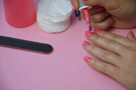 The girl does manicure nails nail file undermining with pink nail polish. Close-up of a hand nearの写真素材