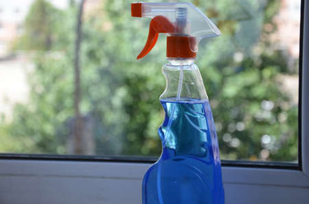 Woman cleaning a window with cleaning sprayer.の写真素材