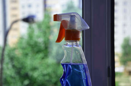 Woman cleaning a window with cleaning sprayer.の写真素材