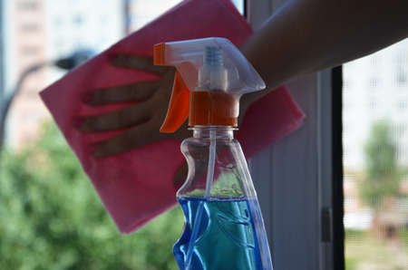 Woman cleaning a window with cleaning sprayer.の写真素材