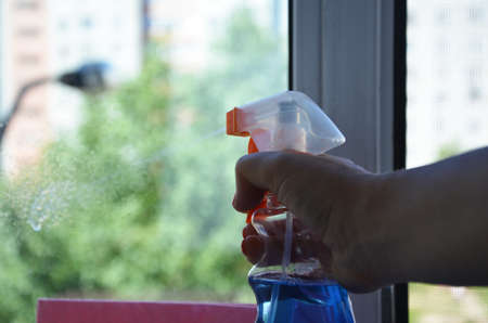 Woman cleaning a window with cleaning sprayer.の写真素材