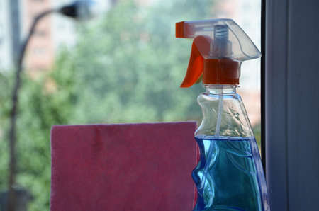 Woman cleaning a window with cleaning sprayer.の写真素材