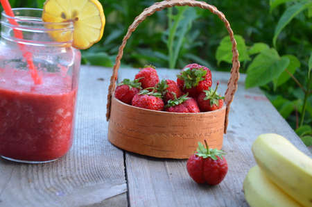 banana and strawberry smoothie in a mason jar on a wooden surface. copy space. top viewの写真素材