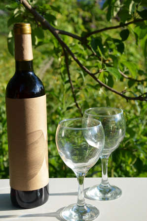 Red wine poured into wine glass on background of green tree leaf foliage. purple flowerの写真素材