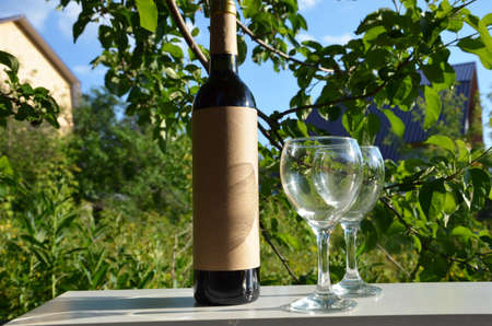 Red wine poured into wine glass on background of green tree leaf foliage. purple flowerの写真素材