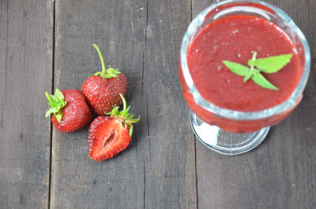 Jars of strawberry jam or jelly with berries and spoon on brown woodwn background close up top view, copy spaceの写真素材