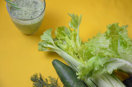 Healthy green smoothie and ingredients on yellow background - superfoods, detox, diet, health, vegetarian food. celery, cucumber, parsley, dill. a diet plan in a notebook.の写真素材
