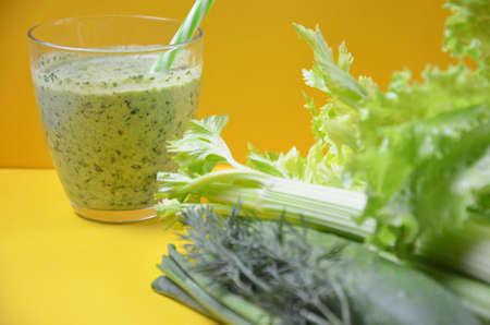 Healthy green smoothie and ingredients on yellow background - superfoods, detox, diet, health, vegetarian food. celery, cucumber, parsley, dill. a diet plan in a notebook.の写真素材