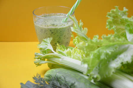 Healthy green smoothie and ingredients on yellow background - superfoods, detox, diet, health, vegetarian food. celery, cucumber, parsley, dill. a diet plan in a notebook.の写真素材