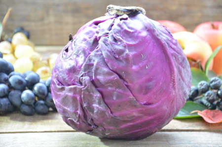 fresh purple red cabbage on cutting board on wood table with copy space. Homemade food concept. Autumn harvest. Background of fruit apples and grapes.の写真素材
