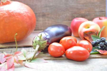 Assortment of fresh fruits and vegetables. autumn harvesting vegetables - eggplant tomatoes zucchini sweet pepper, pumpkin. Autumn leaves on a wooden background.の写真素材