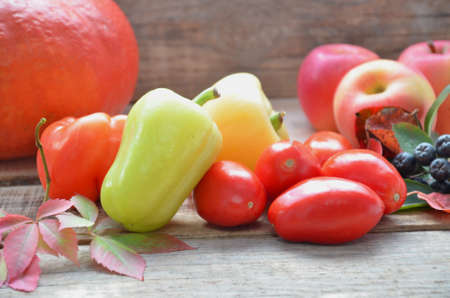 Assortment of fresh fruits and vegetables. autumn harvesting vegetables - eggplant tomatoes zucchini sweet pepper, pumpkin. Autumn leaves on a wooden background.の写真素材