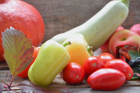 Assortment of fresh fruits and vegetables. autumn harvesting vegetables - eggplant tomatoes zucchini sweet pepper, pumpkin. Autumn leaves on a wooden background.の写真素材