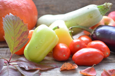 Assortment of fresh fruits and vegetables. autumn harvesting vegetables - eggplant tomatoes zucchini sweet pepper, pumpkin. Autumn leaves on a wooden background.の写真素材