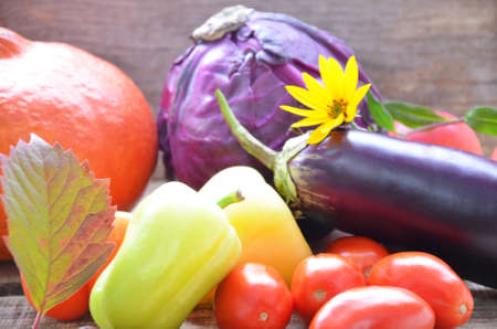 Assortment of fresh fruits and vegetables. autumn harvesting vegetables - eggplant tomatoes zucchini sweet pepper, pumpkin. Autumn leaves on a wooden background.の写真素材