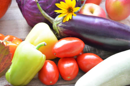 Assortment of fresh fruits and vegetables. autumn harvesting vegetables - eggplant tomatoes zucchini sweet pepper, pumpkin. Autumn leaves on a wooden background.の写真素材