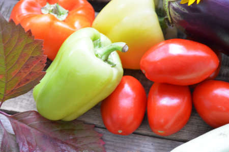Assortment of fresh fruits and vegetables. autumn harvesting vegetables - eggplant tomatoes zucchini sweet pepper, pumpkin. Autumn leaves on a wooden background.の写真素材