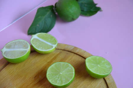 Background from a slices, whole of lime fruits with leaves on pink background. to make a drink of lemonade, tea, cocktail, mojito, detoxの写真素材