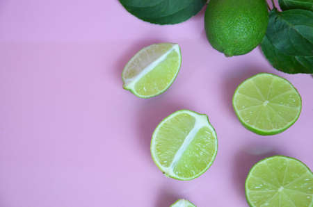 Background from a slices, whole of lime fruits with leaves on pink background. to make a drink of...