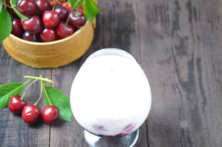 Cherry yogurt dessert or pudding and ripe cherry on a wooden table. Summer dessert.の写真素材