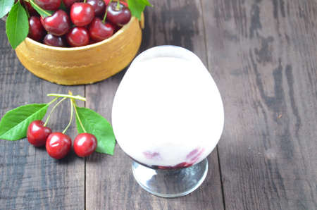 Cherry yogurt dessert or pudding and ripe cherry on a wooden table. Summer dessert.の写真素材