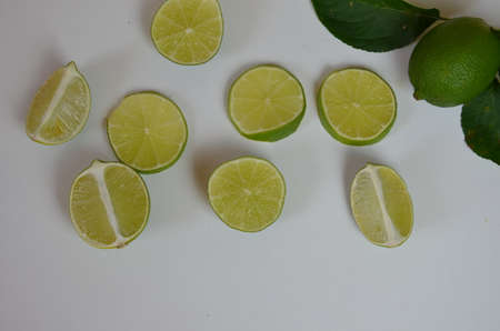 Flat lay of citrus fruits like lime and lemon with lemon tree leaves on light pink background making...