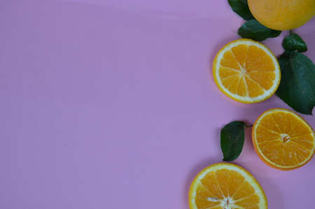 Flat lay of citrus fruits like lime and lemon with lemon tree leaves on light pink background making...