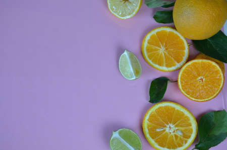 Flat lay of citrus fruits like lime and lemon with lemon tree leaves on light pink background making a frame.の写真素材