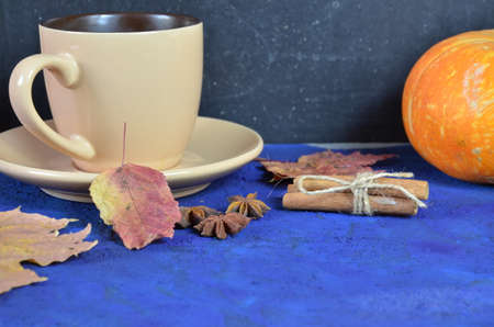 Pumpkin spiced latte or coffee in cup, dry leaves, gifts on dark blue table. Autumn or winter hot drink. Space for text, top view, copy spaceの写真素材