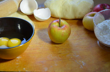 Home autumn, summer baking, puff pastries. Apple strudel with nuts, raisins, cinnamon and powdered sugar. On wooden table. Sliced, with ingredients. Copy space top view. pie ingredientsの写真素材