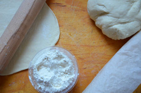 Home autumn, summer baking, puff pastries. Apple strudel with nuts, raisins, cinnamon and powdered sugar. On wooden table. Sliced, with ingredients. Copy space top view. pie ingredientsの写真素材