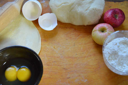 Home autumn, summer baking, puff pastries. Apple strudel with nuts, raisins, cinnamon and powdered sugar. On wooden table. Sliced, with ingredients. Copy space top view. pie ingredientsの写真素材