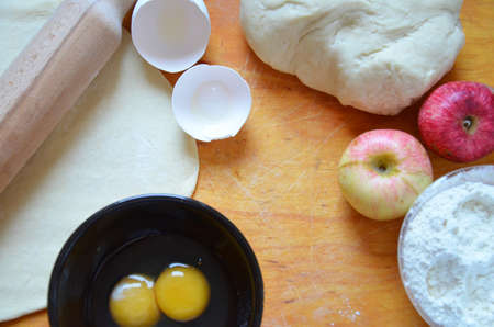 Home autumn, summer baking, puff pastries. Apple strudel with nuts, raisins, cinnamon and powdered sugar. On wooden table. Sliced, with ingredients. Copy space top view. pie ingredientsの写真素材