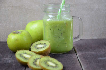 Green healthy smoothie in glass jar: banana, kiwi, green apple on rustic backgroundの写真素材