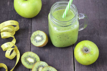 Green healthy smoothie in glass jar: banana, kiwi, green apple on rustic backgroundの写真素材