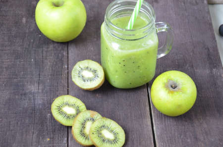 Green healthy smoothie in glass jar: banana, kiwi, green apple on rustic backgroundの写真素材