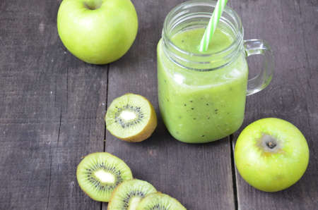 Green healthy smoothie in glass jar: banana, kiwi, green apple on rustic backgroundの写真素材