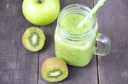 Green healthy smoothie in glass jar: banana, kiwi, green apple on rustic backgroundの写真素材