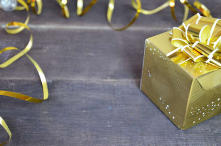 with gold ribbon and bow for a birthday or holiday on a brown wooden backgroundの写真素材