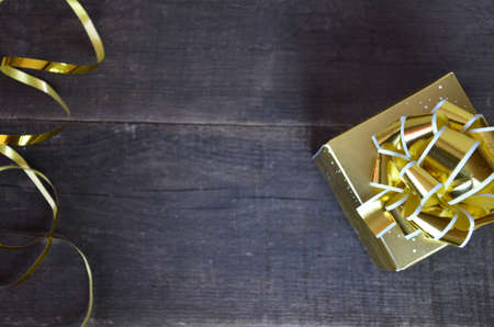 with gold ribbon and bow for a birthday or holiday on a brown wooden backgroundの写真素材