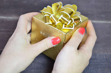 with gold ribbon and bow for a birthday or holiday on a brown wooden backgroundの写真素材