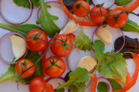 Colorful salad ingredients pattern made of tomatoes, Ruccola, purple onion rings, red sweet pepper, chili, garlic, cucumber slices and basil on white background. Cooking concept. Top view. Flat layの写真素材