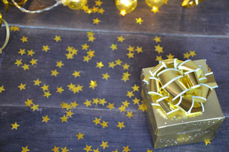 with gold ribbon and bow for a birthday or holiday on a brown wooden background